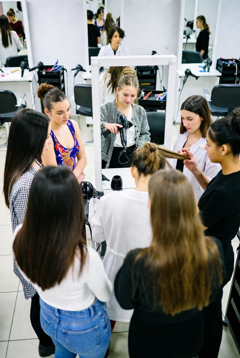 Diverse group of cosmetology students and their instructor in Texas classroom discussing how to become a cosmetology instructor in texas